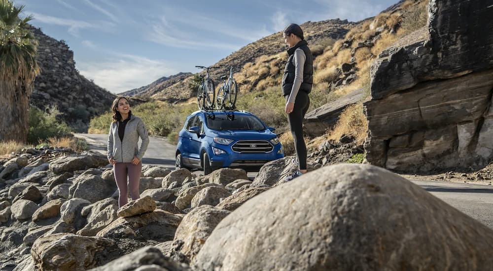 A couple is shown standing near a 2022 Ford EcoSport parked near a hiking area.