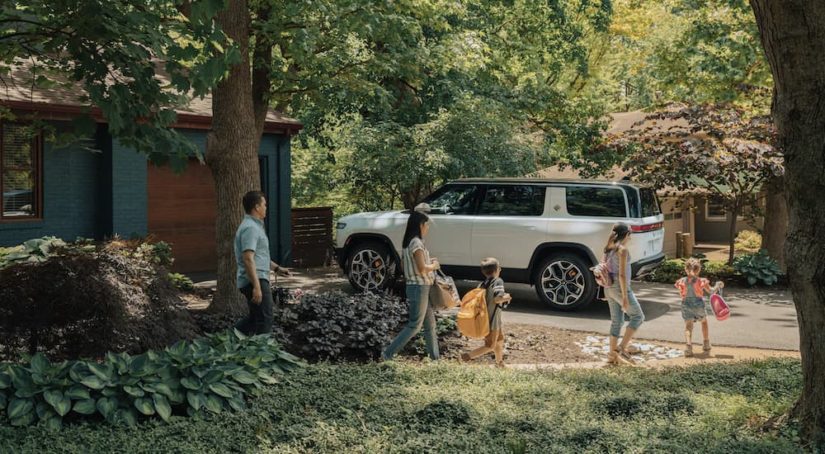 A white 2022 Rivian R1S is shown parked in a driveway.