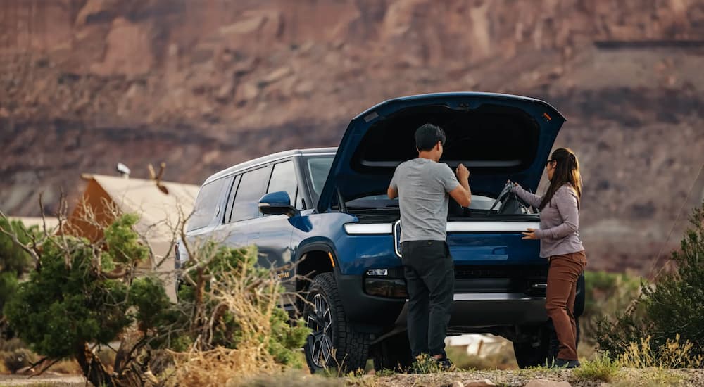 People are shown stowing luggage in a blue 2022 Rivian R1S.