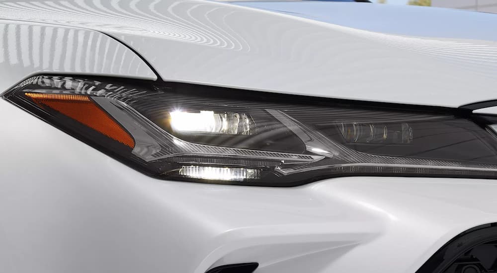 A close up of the headlight on a white 2022 Toyota Avalon Hybrid is shown.