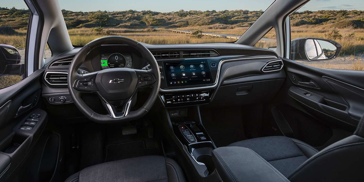The black interior of a 2023 Chevy Bolt EV shows the steering wheel and center console.