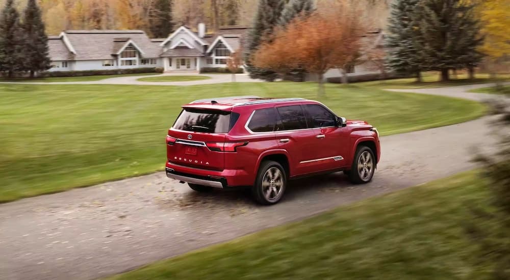 A red 2023 Toyota Sequoia is shown from the rear at an angle while driving though a suburb.