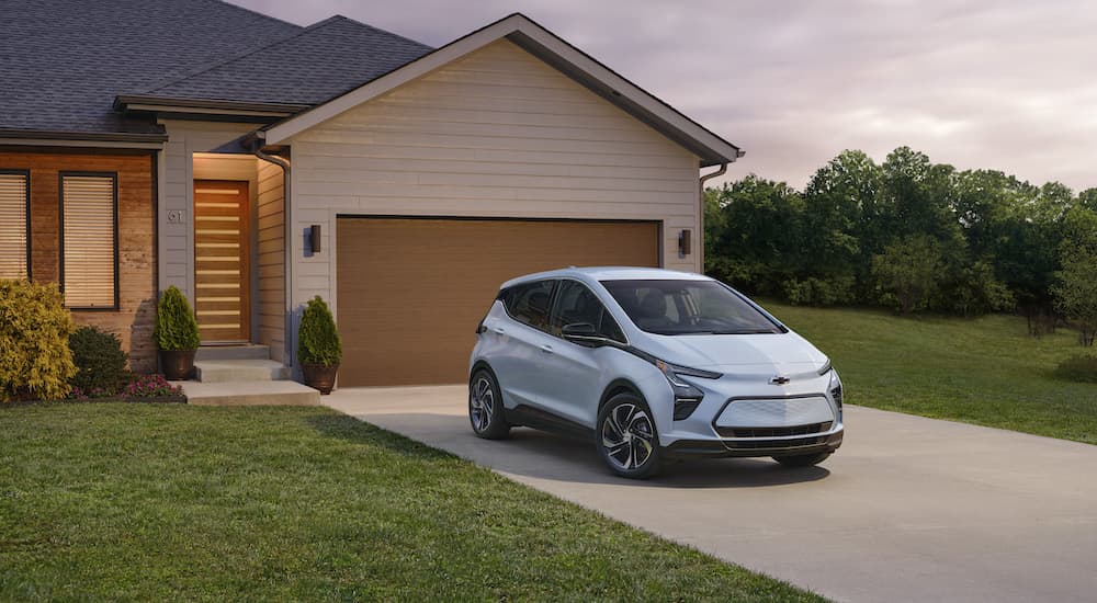 A light blue 2023 Chevy Bolt EV is shown from the front at an angle while parked in a driveway.