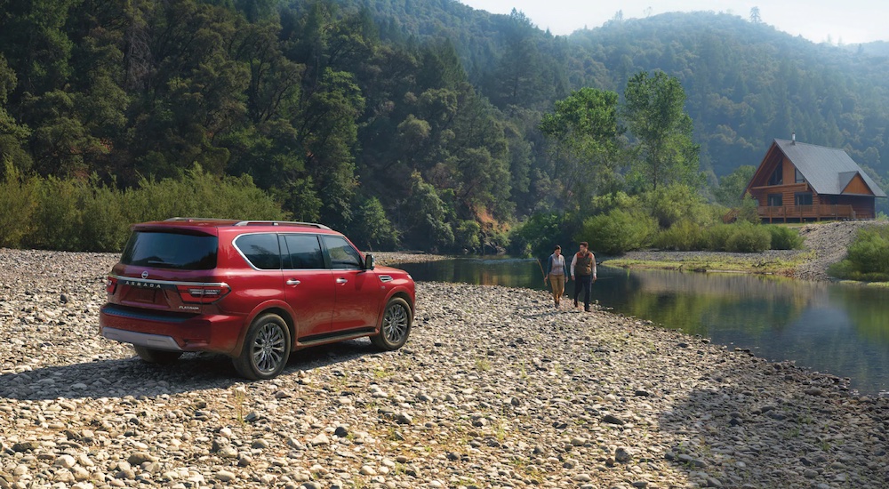A red 2022 Nissan Armada is shown from the rear at an angle while parked on a rocky shore.