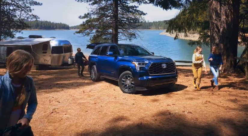 A blue 2023 Toyota Sequoia is shown from the front at an angle while parked near a lake.