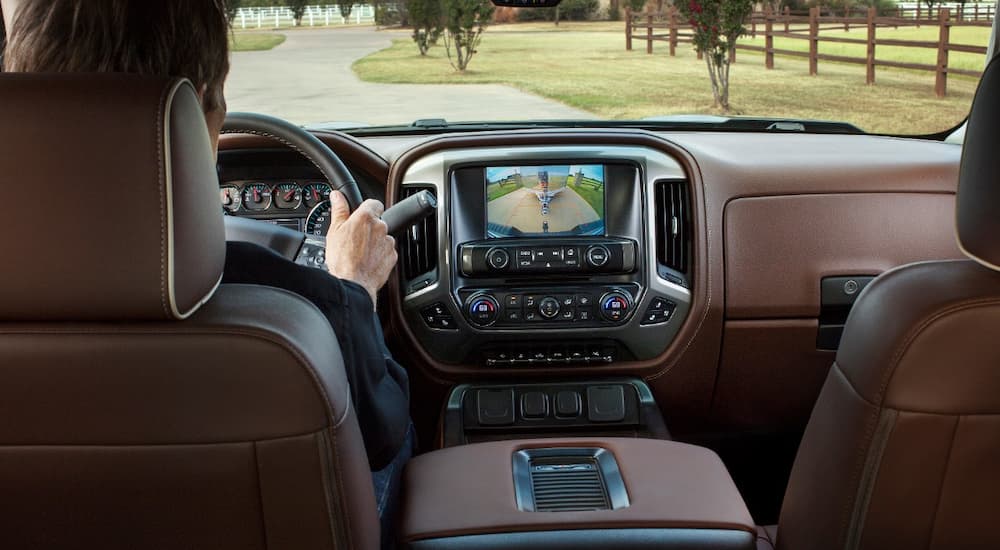 A person is shown driving a 2018 Chevy Silverado 1500 High Country after leaving a Chevy dealership.