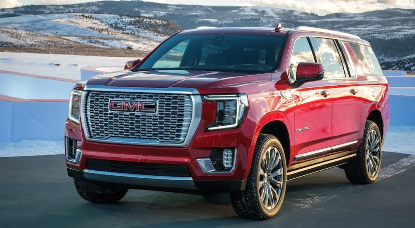 A red 2022 GMC Yukon is shown from the front at an angle while driving down the road after leaving a GMC dealer.