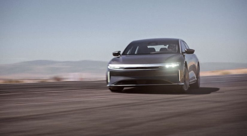 A grey 2022 Lucid Air GT is shown from the front at an angle while rounding a corner at speed.
