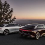 A white and a black 2022 Lucid Air GT are shown from behind on an overlook.