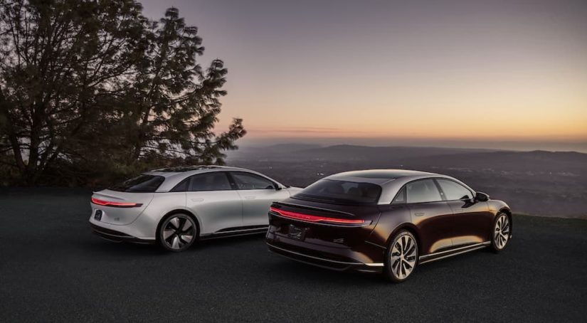 A white and a black 2022 Lucid Air GT are shown from behind on an overlook.