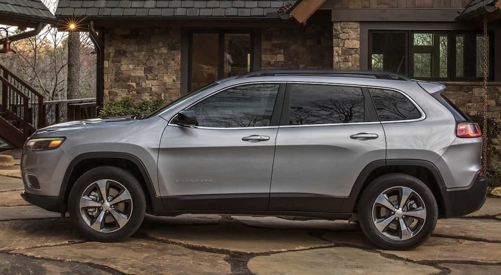 A grey 2022 Jeep Cherokee Limited 4x4 is shown from the side parked in front of a building.