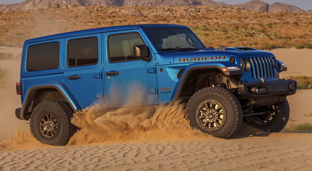 A blue 2022 Jeep Wrangler Rubicon 392 is shown driving through a desert after searching 'Jeep lease deals.'