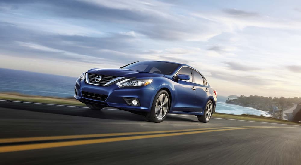A blue 2018 Nissan Altima is shown from the side driving on the coast.