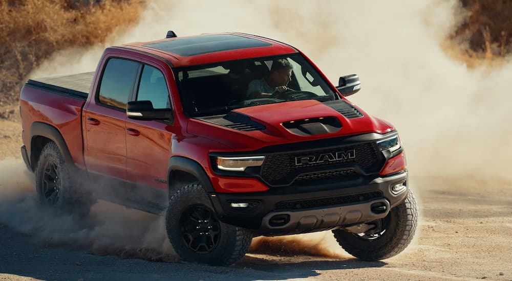 A red 2022 Ram 1500 TRX is shown off-roading after visiting a Ram 1500 dealership.