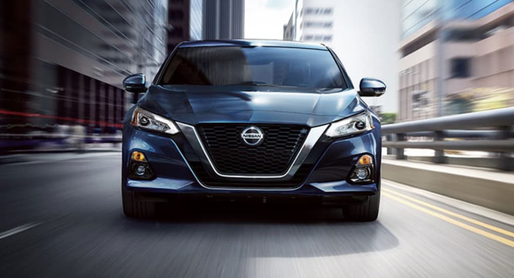A blue 2020 Nissan Altima is shown from the front driving on an open road.