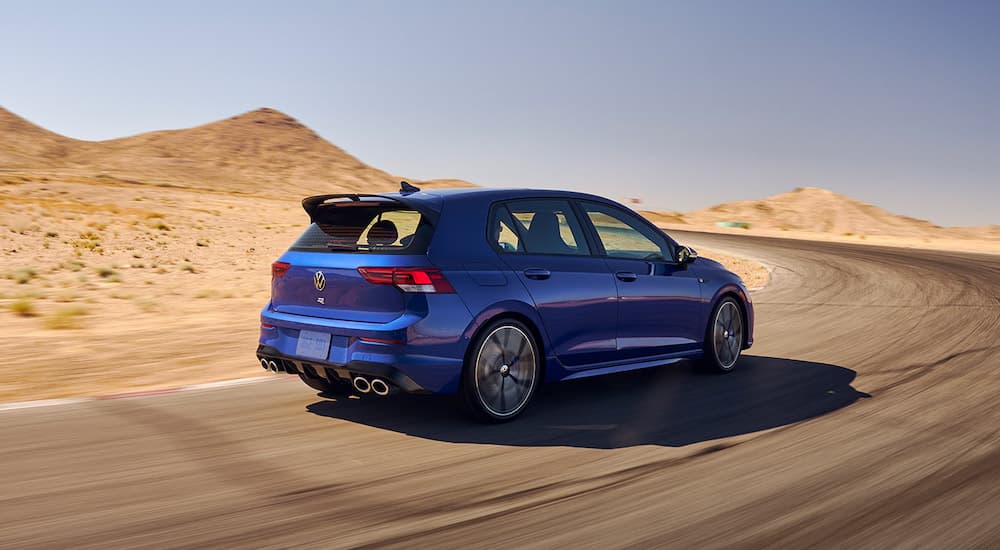 A blue 2022 VW Golf R is shown from the rear at an angle while on a desert road.