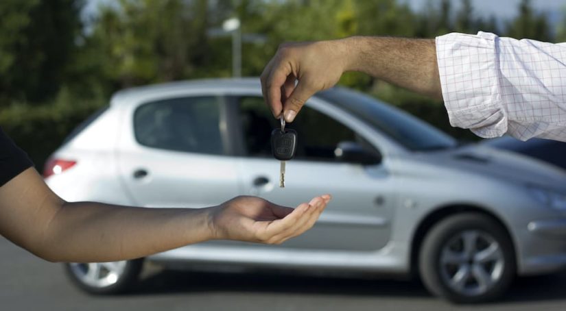 A person is shown passing a car key after deciding to search 'sell your car.'