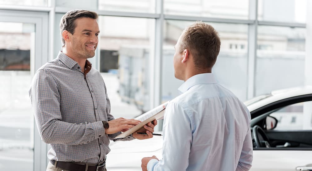 A car salesman is shown negotiating with a customer.