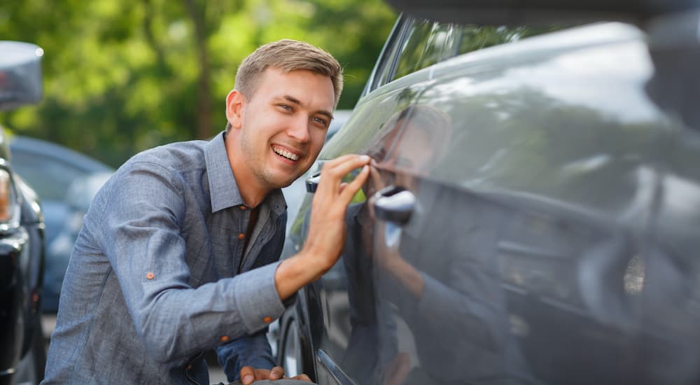 A person is shown looking at a grey car.