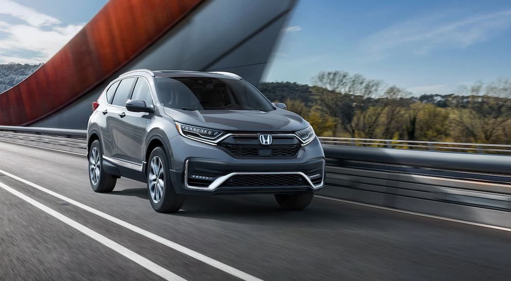 A grey 2020 Honda CR-V Hybrid is shown from the front at an angle while driving over a bridge.