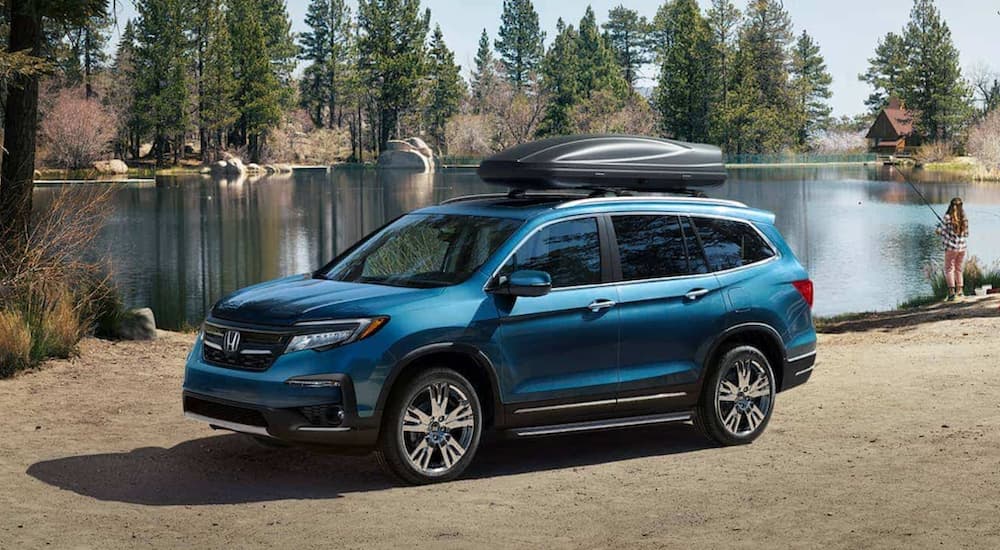 A blue 2021 Honda Pilot is shown parked on a lakeshore.
