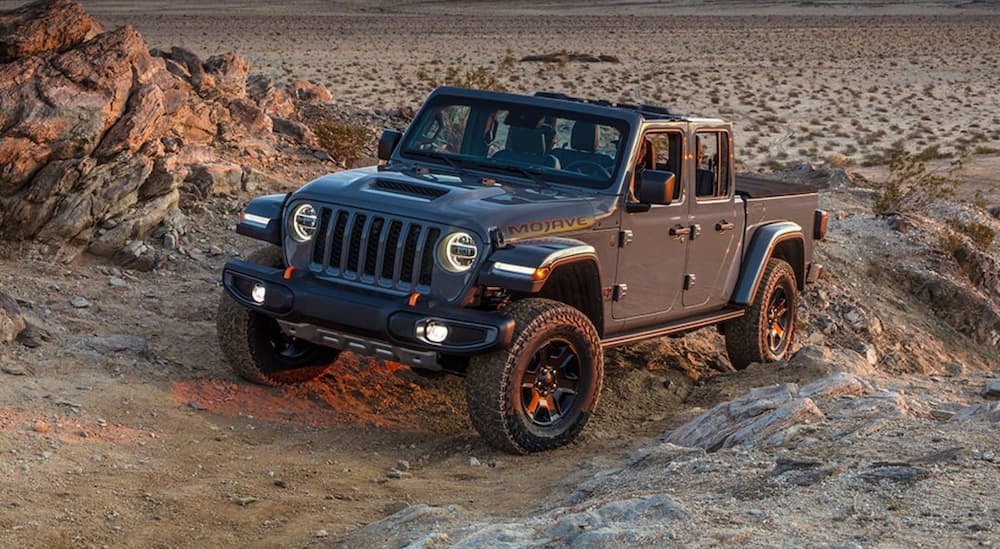 A grey 2021 Jeep Gladiator Mojave is shown from the front while driving off-road after leaving a used truck dealer.