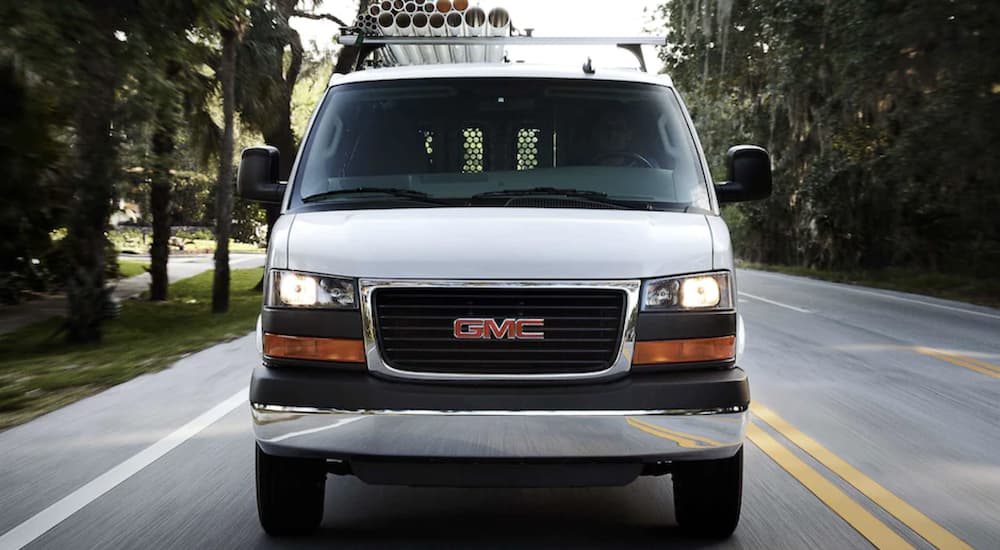 A white 2022 GMC Savana Cargo Van is shown from the front driving on an open road.