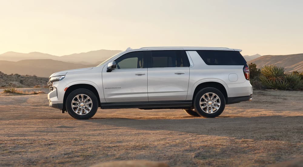 A white 2023 Chevy Suburban is shown from the side in the desert.