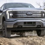 A silver 2022 Ford F-150 Lightning is shown from the front at a low angle after leaving a Ford dealer.