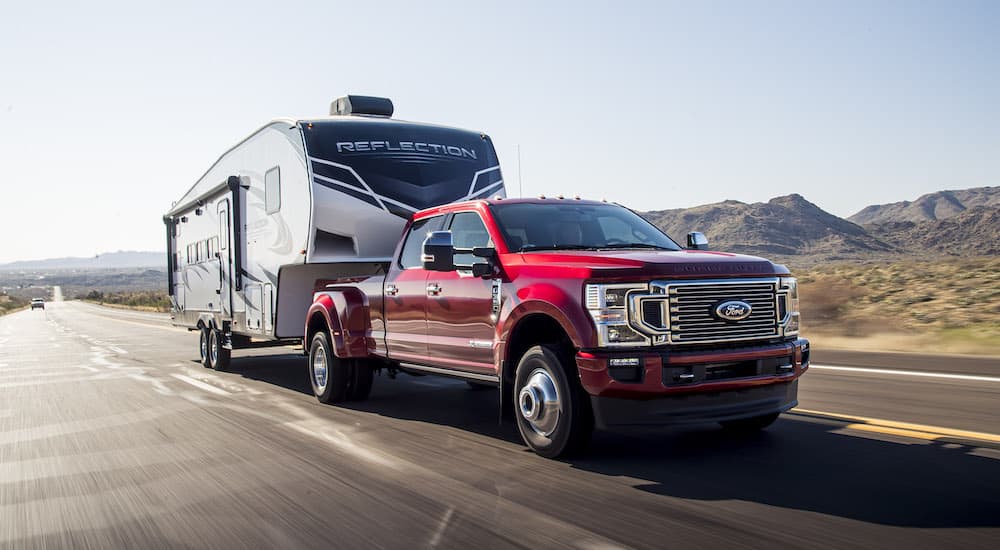 A red 2022 Ford F-350 Dually Platinum is shown from the front while towing a camper.