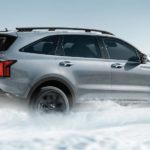 A silver 2022 Kia Sorento is shown driving through snow after leaving a Kia dealer.