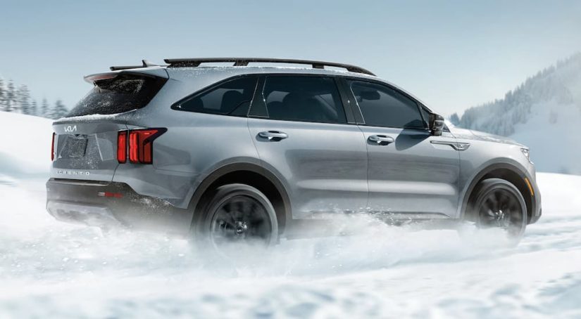 A silver 2022 Kia Sorento is shown driving through snow after leaving a Kia dealer.