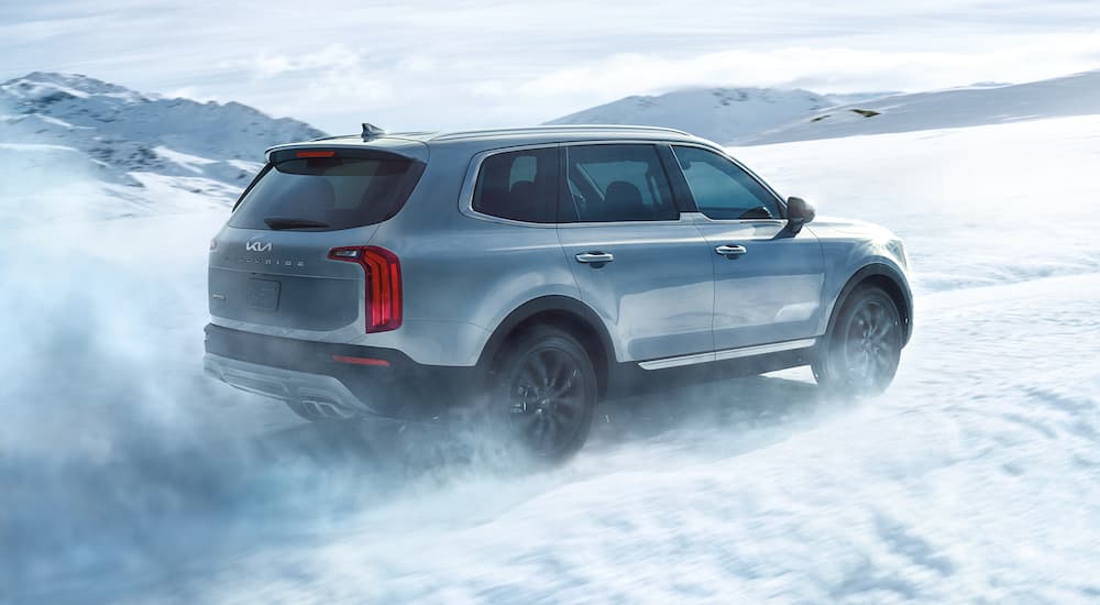 A grey 2022 Kia Telluride is shown from the side kicking up snow.