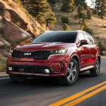 A red 2022 Kia Sorento Hybrid is shown rounding a corner after leaving a Kia Sorento dealer.