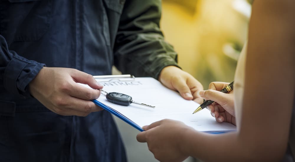 A person is shown signing lease paperwork.