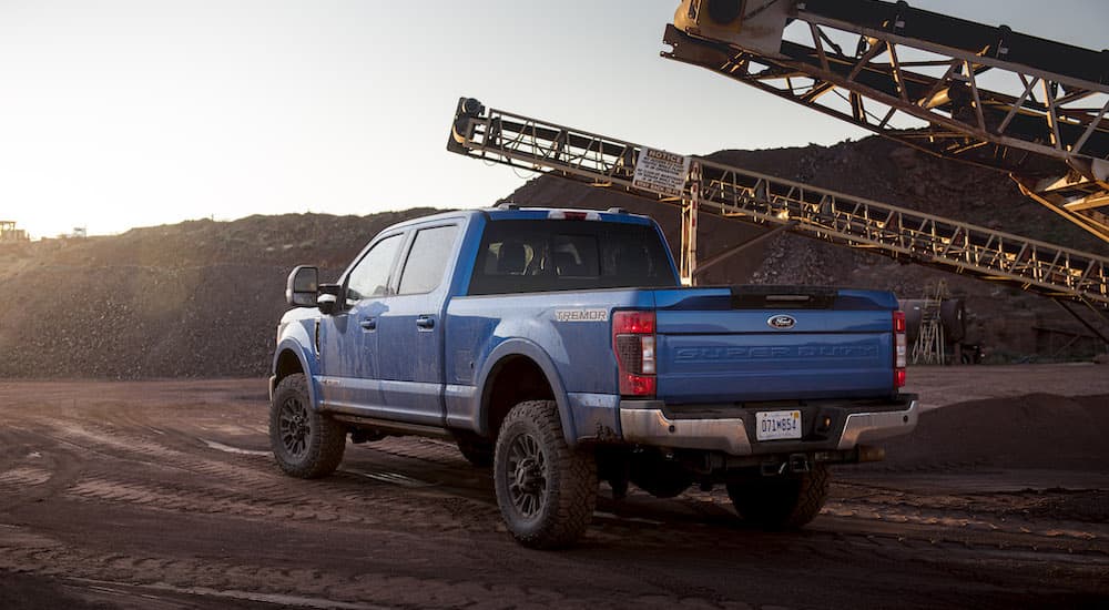 A blue 2022 Ford F-350 Tremor is shown from the rear at an angle while parked on a jobsite.