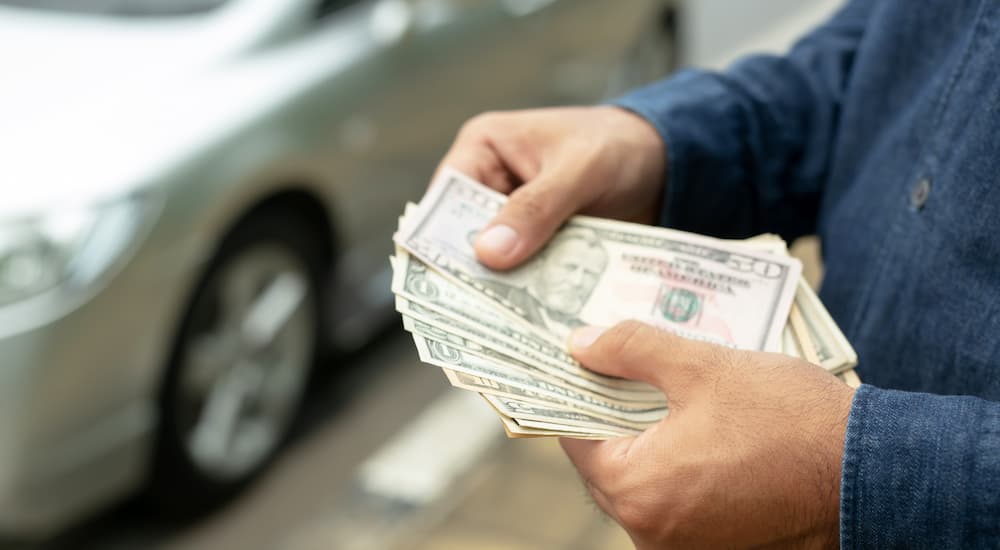 A person is shown counting cash after selling their vehicle.