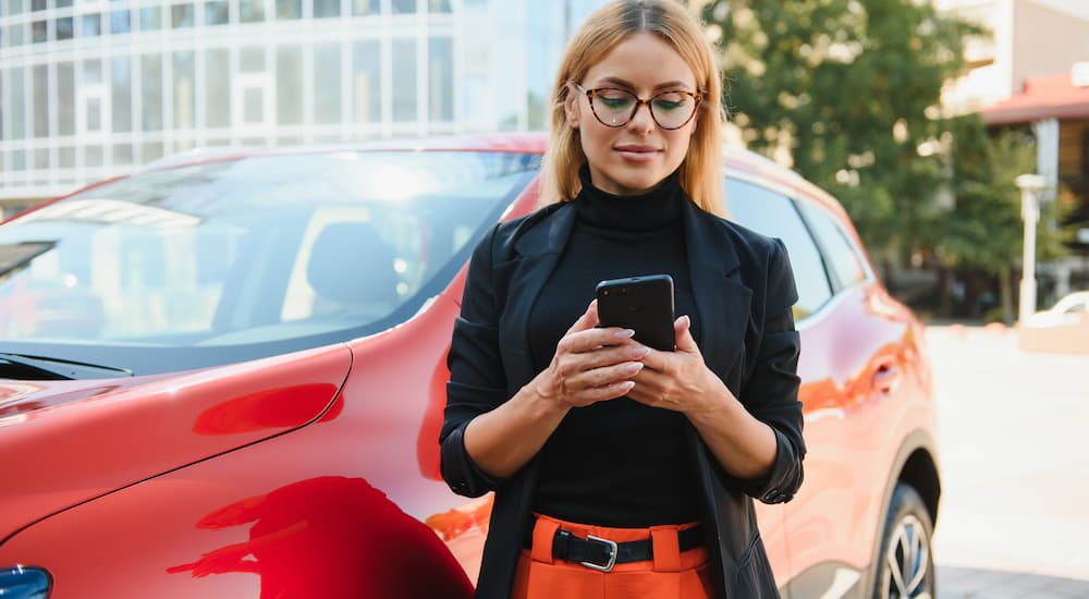 A woman is shown on her phone while trying to sell her car.