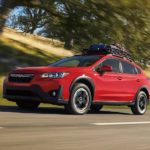 A red 2023 Subaru Crosstrek Premium is shown driving on an open road.