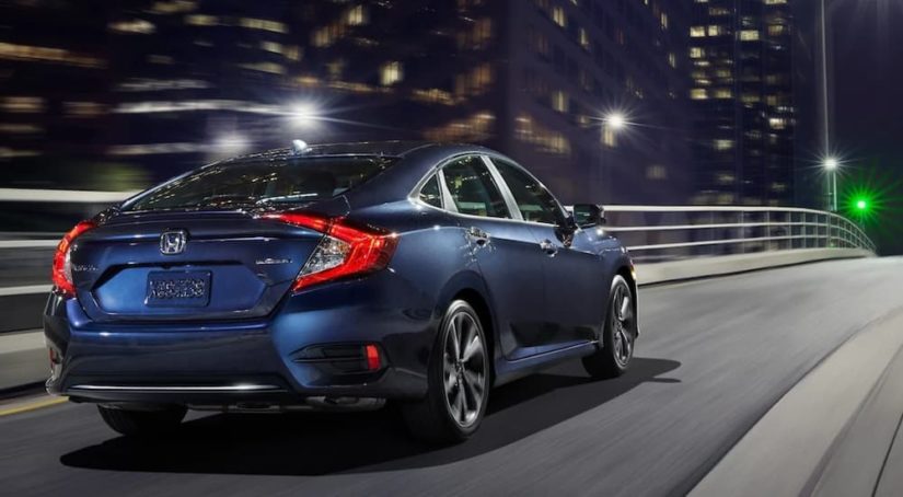 A blue 2020 Honda Civic is shown from the rear driving on an open road.