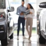 A couple is shown at a dealership looking at their car's trade in value.