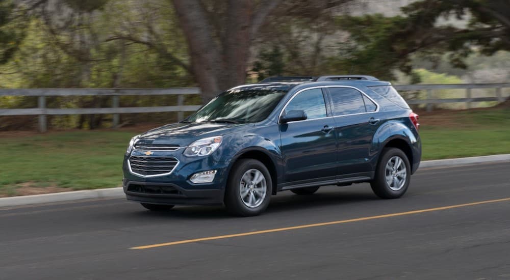 A blue 2016 Chevy Equinox is shown from the side while driving down the road.