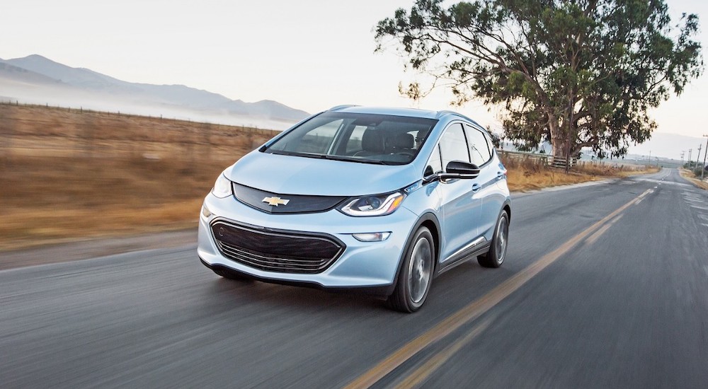 A blue 2017 Chevy Bolt EV is shown from the front while driving after the owner searched for 'how to sell my car'.