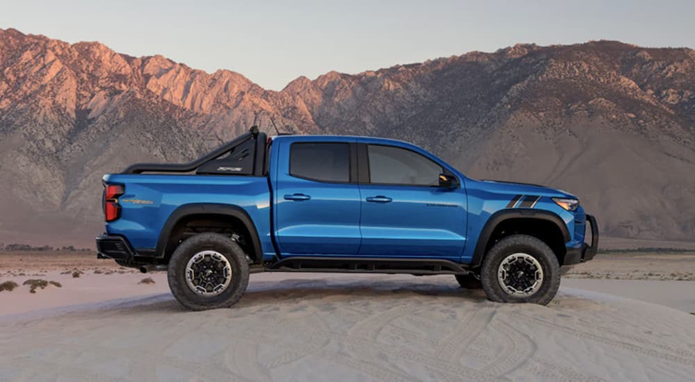 A blue 2023 Chevy Colorado Trail Boss is shown parked in a desert.