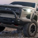A tan 2023 Chevy Colorado ZR2 is shown from the front parked in a desert.