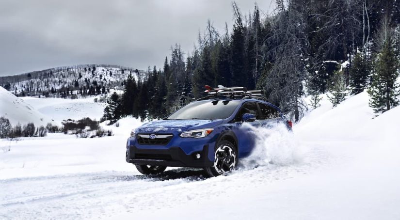 A blue 2023 Subaru Crosstrek is shown from the front at an angle while driving through snow.