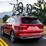 A red 2022 Kia Sorento Hybrid for sale near you is shown driving on an open road.
