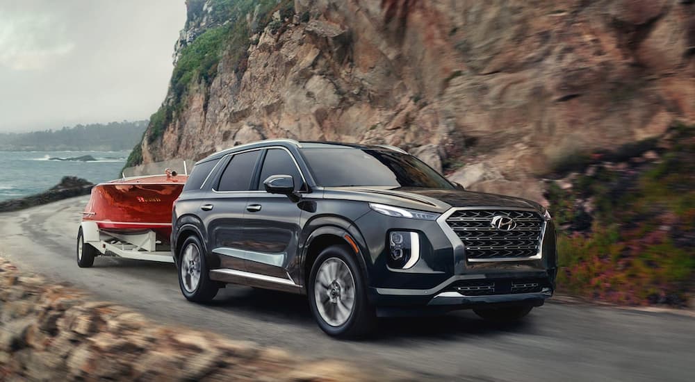 A grey 2022 Hyundai Palisade is shown from the front at an angle while towing a boat during a 2022 Ford Explorer vs 2022 Hyundai Palisade comparison.