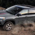 A grey 2023 Jeep Compass is shown off-roading.