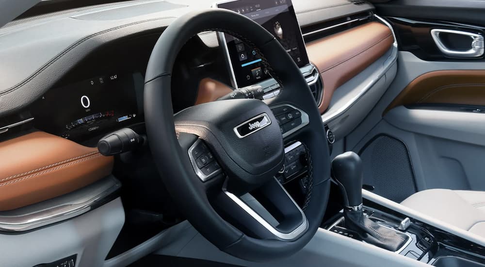 The black and brown interior of a 2023 Jeep Compass shows the steering wheel.